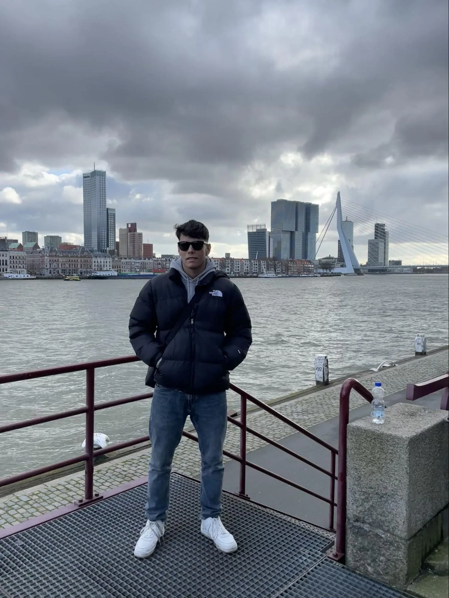 Samuel López junto al agua Samuel López posando frente al río en Róterdam con el puente Erasmus de fondo.